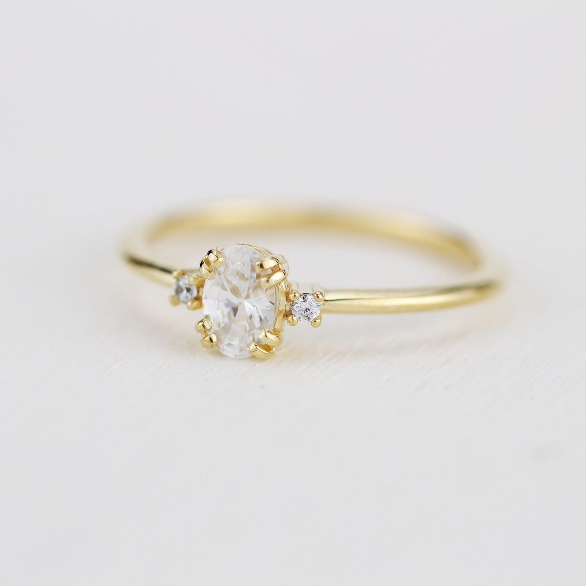 18k gold three-stone ring with an oval lab grown diamond, angled view
