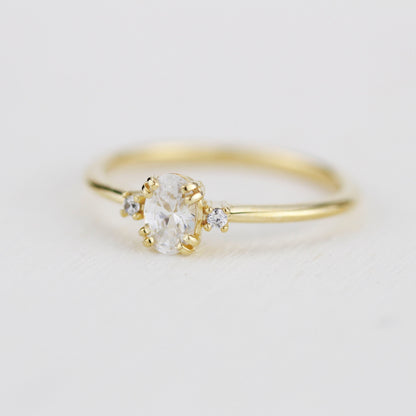 18k gold three-stone ring with an oval lab grown diamond, angled view