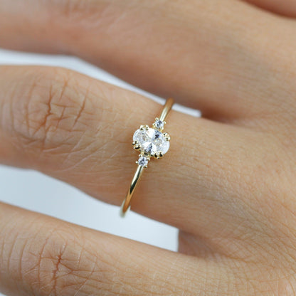 18k gold three-stone ring with an oval lab grown diamond, worn on the hand, close view