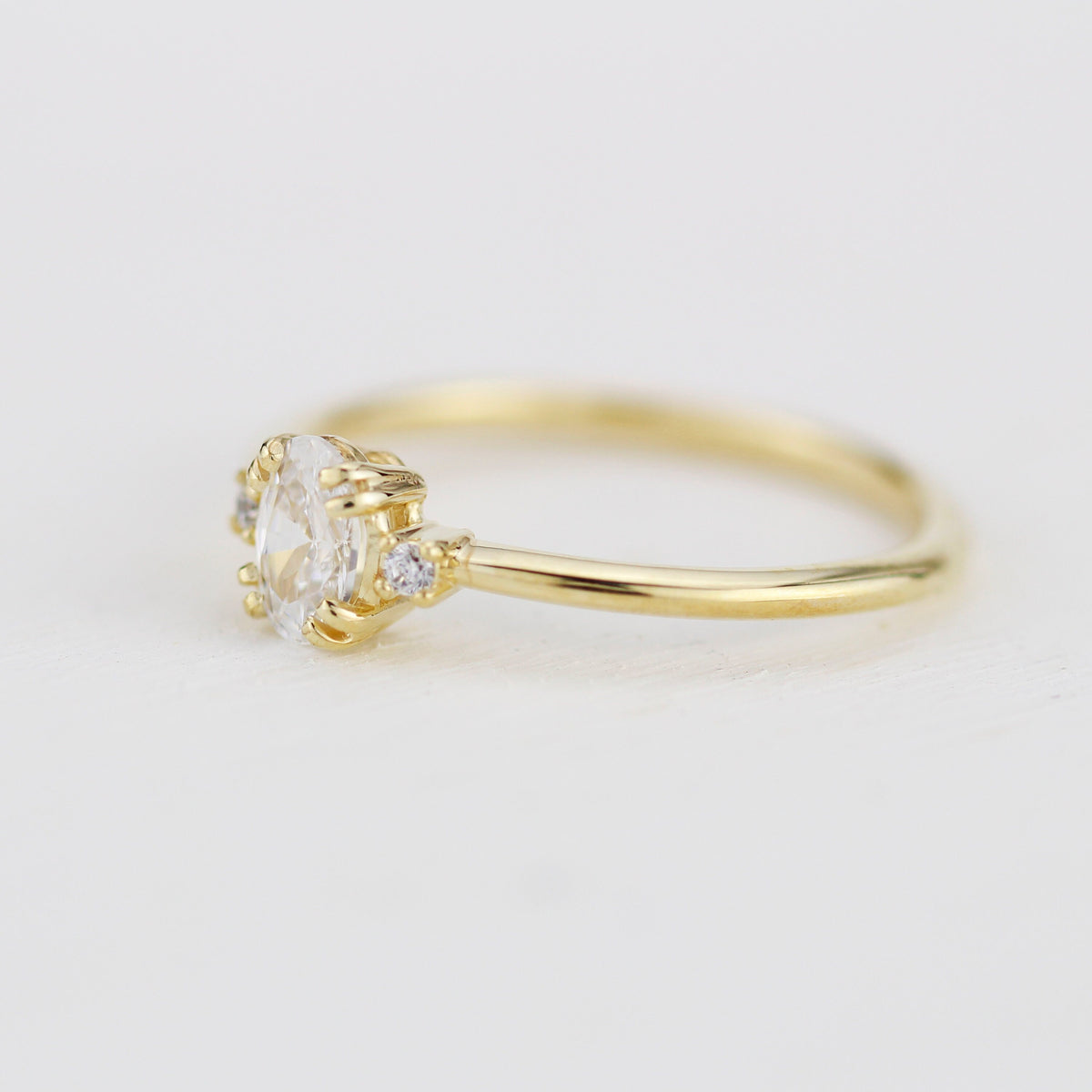 18k gold three-stone ring with an oval lab grown diamond, side view
